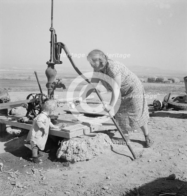 Mrs. Soper with youngest child at the well, Willow creek area, Malheur County, Oregon, 1939. Creator: Dorothea Lange.