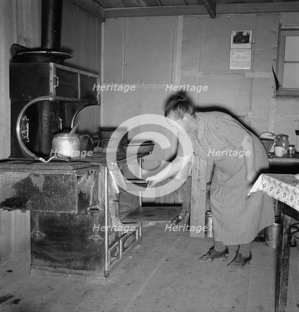 Mrs. Wardlow baking corn bread in her dugout basement home, Dead Ox Flat, Oregon, 1939. Creator: Dorothea Lange.