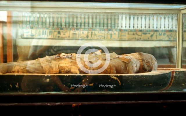 Mummy wrapped in bandages and lying on the base of a coffin, Ancient Egyptian. Artist: Unknown