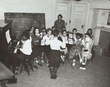 Music classes, tambourines and piano, 1938. Creator: Aubrey Pollard