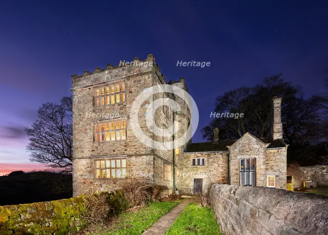 North Lees Hall from the south-east with the windows illuminated, Hathersage, Derbyshire, 2025.  Creator: Alun Bull.