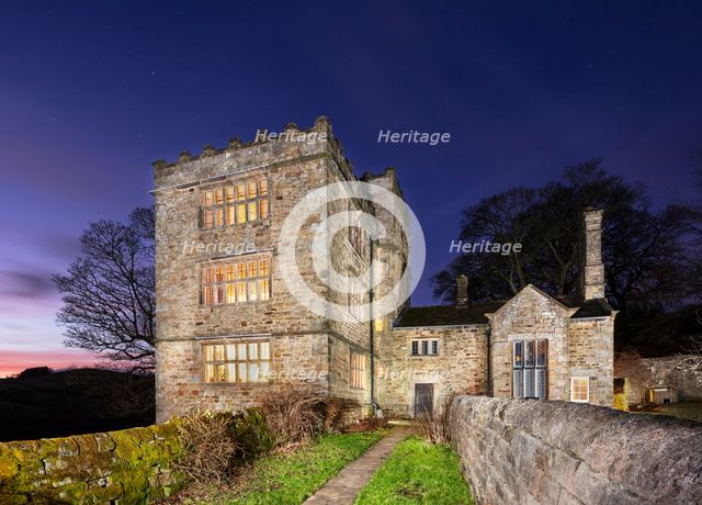 North Lees Hall from the south-east with the windows illuminated, Hathersage, Derbyshire, 2025.  Creator: Alun Bull.