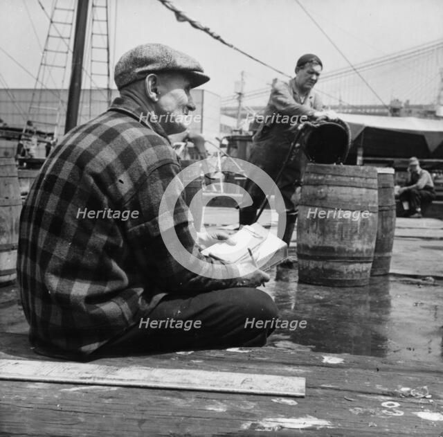 New England fisherman checking baskets of fish as they are lifted from his ship, New York, 1943. Creator: Gordon Parks.