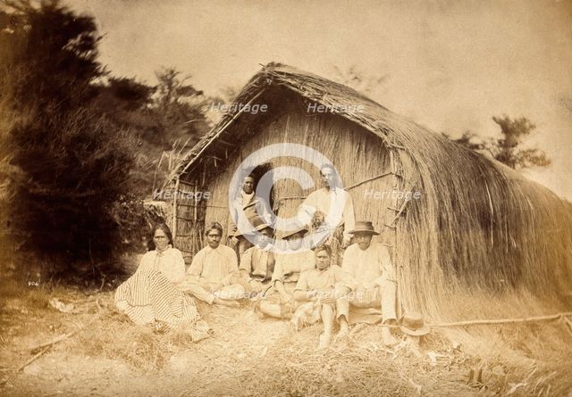 New Zealand: a group of Maori sitting in front of a traditional house, between 1800 and 1899. Creator: Unknown.