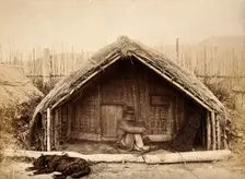 New Zealand: a Maori man sitting in front of a traditional house, between 1800 and 1899. Creator: Unknown