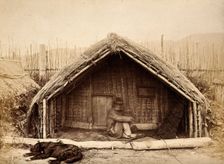 New Zealand: a Maori man sitting in front of a traditional house, between 1800 and 1899. Creator: Unknown