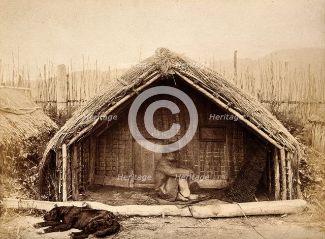 New Zealand: a Maori man sitting in front of a traditional house, between 1800 and 1899. Creator: Unknown.