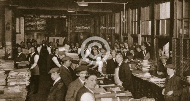 Newsvendors gather to pick up the next day's newspapers to sell, Carmelite House, 20th century. Creator: Unknown.