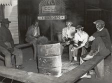 Negro laborers sitting around in front of a fire on Saturday night in a street of the..., Feb 1941. Creators: Farm Security Administration, Marion Post Wolcott