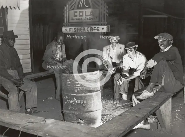 Negro laborers sitting around in front of a fire on Saturday night in a street of the..., Feb 1941. Creators: Farm Security Administration, Marion Post Wolcott.