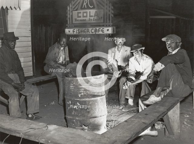 Negro laborers sitting around in front of a fire on Saturday night in a street of the..., Feb 1941. Creators: Farm Security Administration, Marion Post Wolcott.