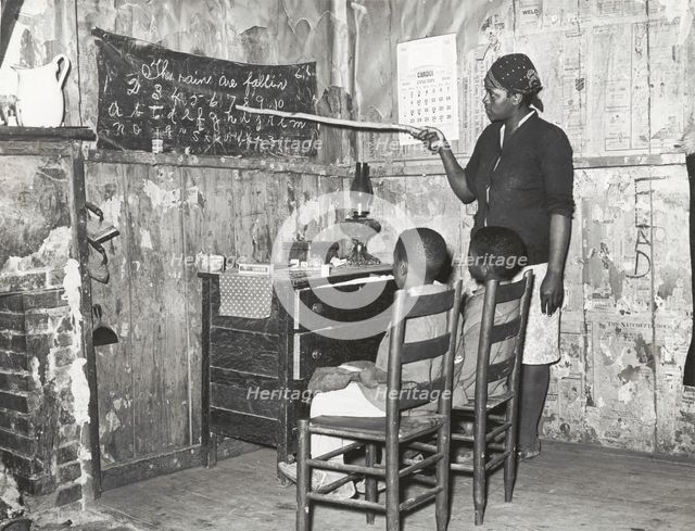 Negro mother teaching children numbers and alphabet in home of sharecropper..., Jan 1939. Creators: Farm Security Administration, Russell Lee.