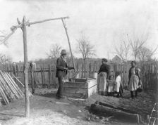 Negro man, woman and three children at an old-time well, 1899 or 1900. Creator: Frances Benjamin Johnston