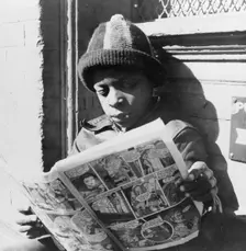 Negro youth reading a funny paper on a door step in the Southwest section, Washington, D.C., 1942. Creator: Gordon Parks