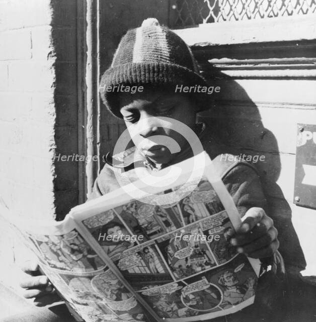Negro youth reading a funny paper on a door step in the Southwest section, Washington, D.C., 1942. Creator: Gordon Parks.
