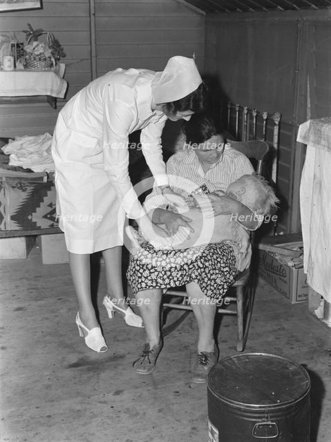 Nurse attending sick baby, FSA camp, Farmersville, Tulare County, California, 1939. Creator: Dorothea Lange.