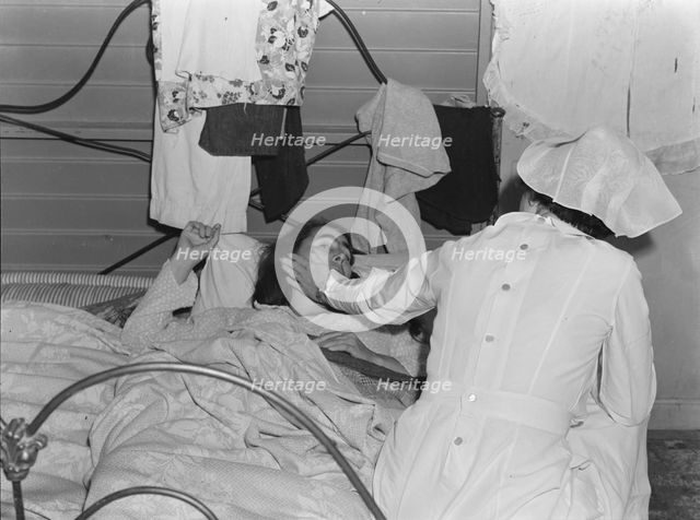 Nurse attending sick migrant woman, FSA camp, Farmersville, Tulare County, California, 1939. Creator: Dorothea Lange.