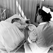 Nurse feeding a child, London, (1960s?). Creator: Henry Grant