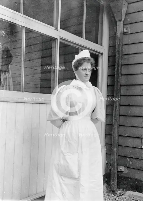 Nurse standing outside an isolation hospital, possibly at Ilford, Essex. Creator: Unknown.