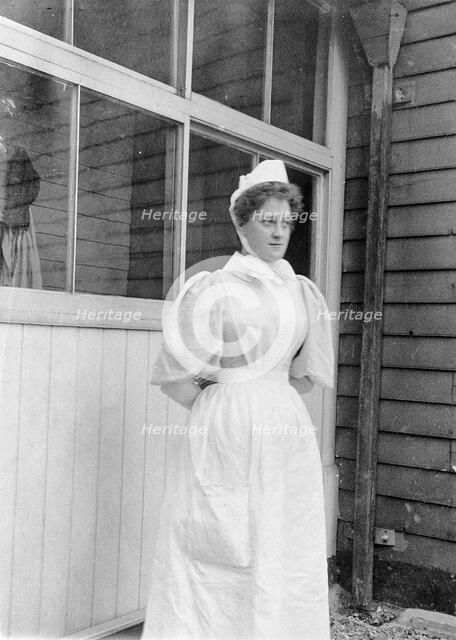 Nurse standing outside an isolation hospital, possibly at Ilford, Essex. Creator: Unknown.
