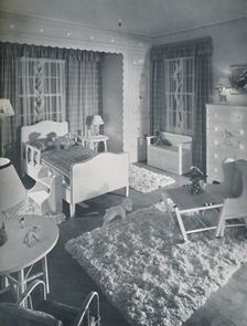 Nursery by W. & J. Sloane, with cream-coloured furniture and shaggy white rugs on a blue painted fl
