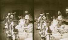 Nurses and a doctor attending wounded soldiers on a hospital ward, c1905. Creator: Underwood & Underwood