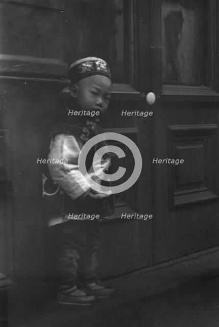 Small boy standing in front of a door, Chinatown, San Francisco, between 1896 and 1906. Creator: Arnold Genthe.