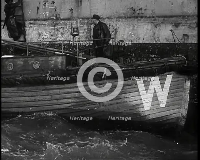 Small Wooden Customs Boat With Male Crew Member Standing at  the Bow End Alongside..., 1939. Creator: British Pathe Ltd.