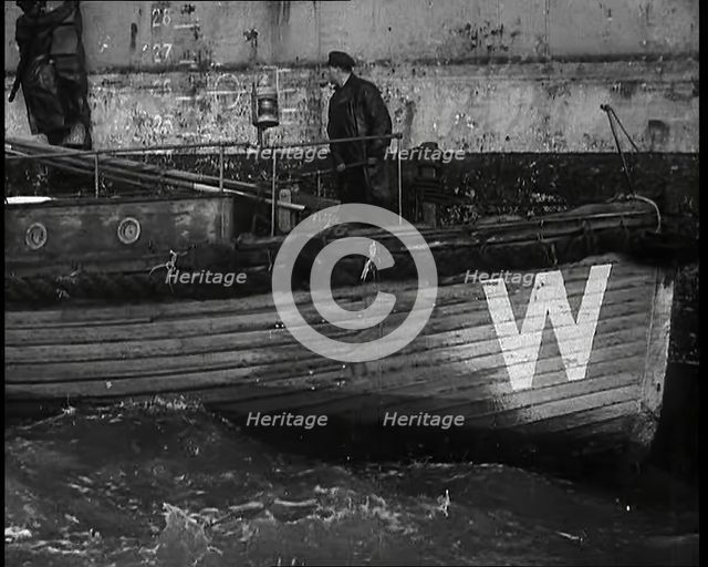 Small Wooden Customs Boat With Male Crew Member Standing at  the Bow End Alongside..., 1939. Creator: British Pathe Ltd.