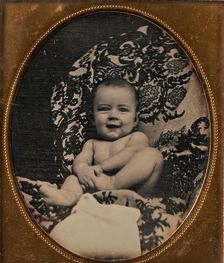 [Smiling, Nude Baby Holding Foot, Seated on Furniture Draped with Floral Print Fabric], 1850s. Creator: Unknown