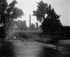 Smokestack by river, probably the Huron River, Ypsilanti, Michigan, between 1900 and 1910. Creator: Unknown
