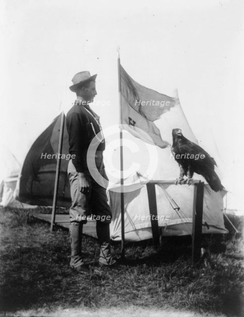 Soldier and eagle mascot beside "H" Troop flag, 1898. Creator: Frances Benjamin Johnston.