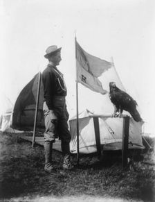Soldier and eagle mascot beside "H" Troop flag, 1898. Creator: Frances Benjamin Johnston