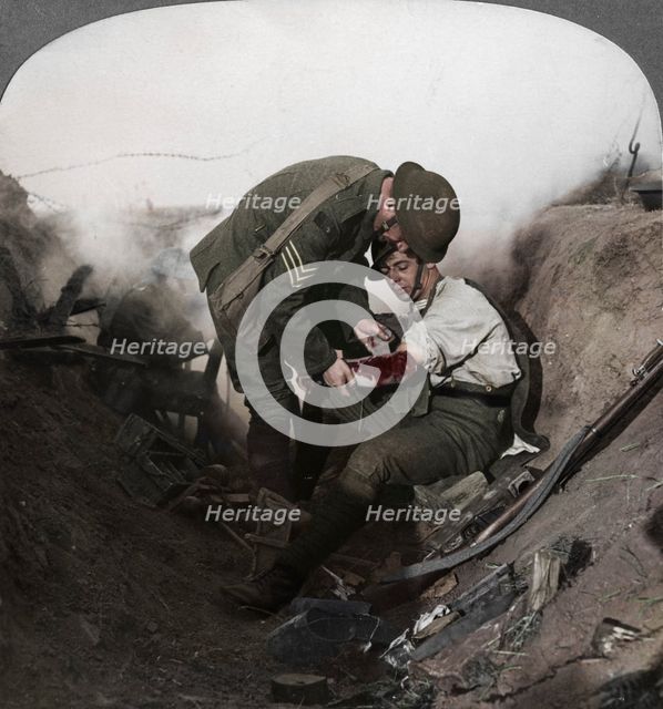 Soldier receiving first aid from a sergeant in a sap, Battle of Peronne, World War I, 1914-1918. Artist: Realistic Travels Publishers.