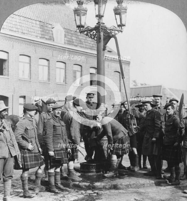 Soldiers filling their water bottles at the town pump La Gorgue, France, World War I, c1914-c1918. Artist: Realistic Travels Publishers