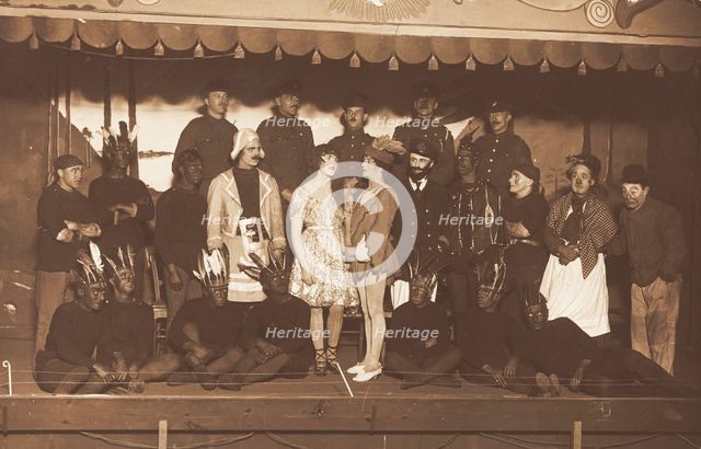 Soldiers, some in drag, pose on stage; two men in drag face each other in the centre, [1910-1919?]. Creator: Unknown.