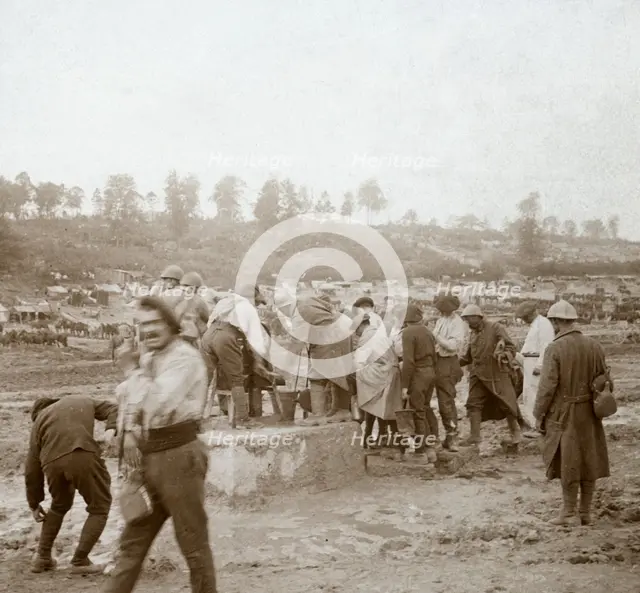 Soldiers queuing in the mud for water, Genicourt, northern France, c1914-c1918. Artist: Unknown.