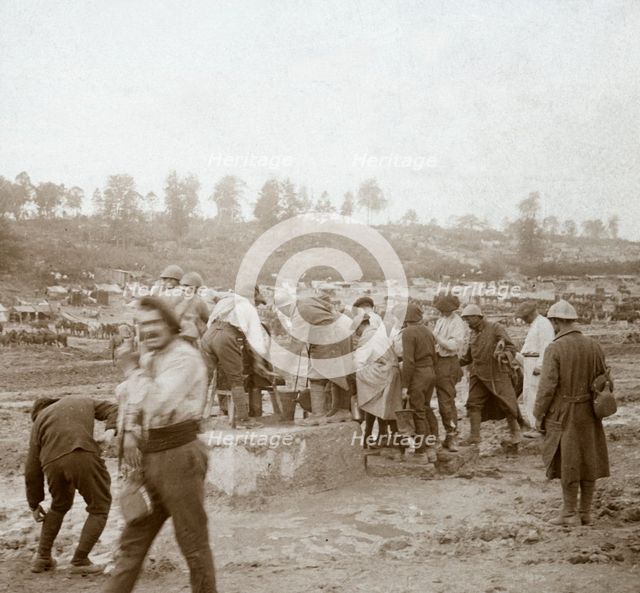 Soldiers queuing in the mud for water, Genicourt, northern France, c1914-c1918. Artist: Unknown.