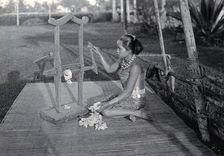 Sarawak: a girl extracting the seeds of raw cotton in a cotton gin, c1900. Creator: Unknown
