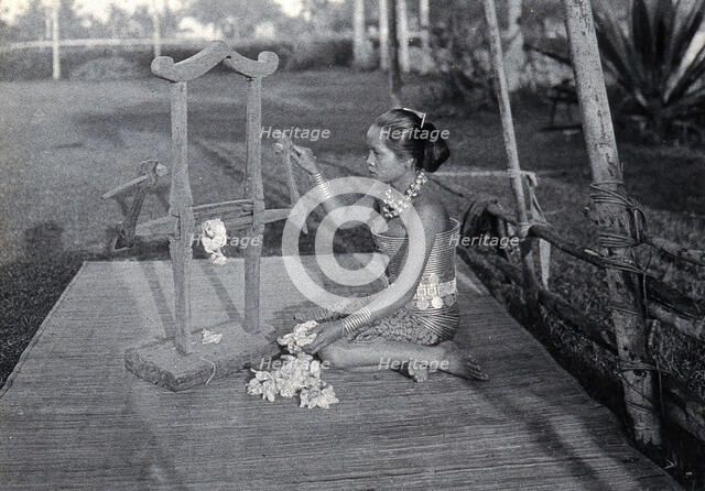 Sarawak: a girl extracting the seeds of raw cotton in a cotton gin, c1900. Creator: Unknown.