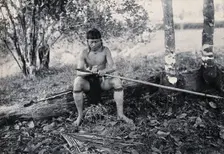 Sarawak: a Kenyah worker tying a spearhead to a blowpipe, c1900. Creator: Unknown