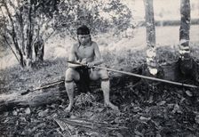 Sarawak: a Kenyah worker tying a spearhead to a blowpipe, c1900. Creator: Unknown