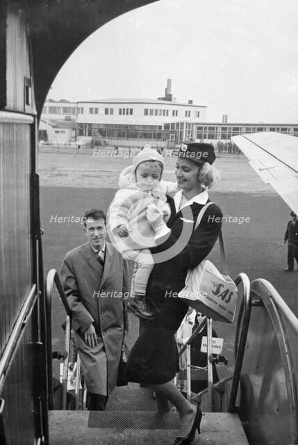 SAS stewardess carrying a baby onto a plane, Bulltofta airport, Malmö, Sweden, 1950. Artist: Torkel Lindeberg
