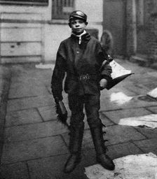 Scavenger boy who cleans up horse droppings in the road, London, 1926-1927