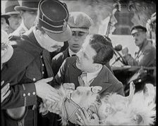 Scene from the Film The Compulsory Husband': Monty Banks Holding a Dog That He Has Run Over, 1920s. Creator: British Pathe Ltd