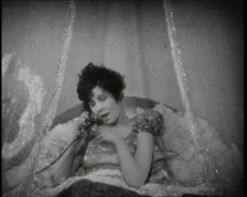 Scene from a 1920s Film. A Female Actor Speaking on the Telephone in Bed Still Wearing Her..., 1920s Creator: British Pathe Ltd