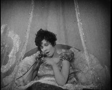 Scene from a 1920s Film. A Female Actor Speaking on the Telephone in Bed Still Wearing Her..., 1920s Creator: British Pathe Ltd