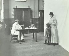 School nurse examining girls hair for head lice, Chaucer School, London, 1911