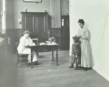 School nurse examining girls hair for head lice, Chaucer School, London, 1911
