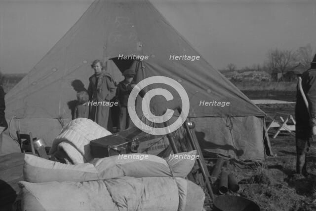 Setting up a tent in the camp for white flood refugees, Forrest City, Arkansas, 1937. Creator: Walker Evans.